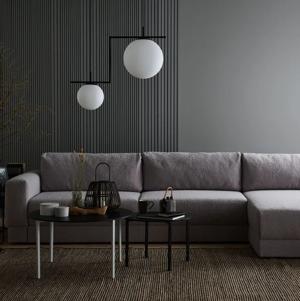 Minimalistyczna szara sofa w eleganckim, ciemnym wnętrzu.